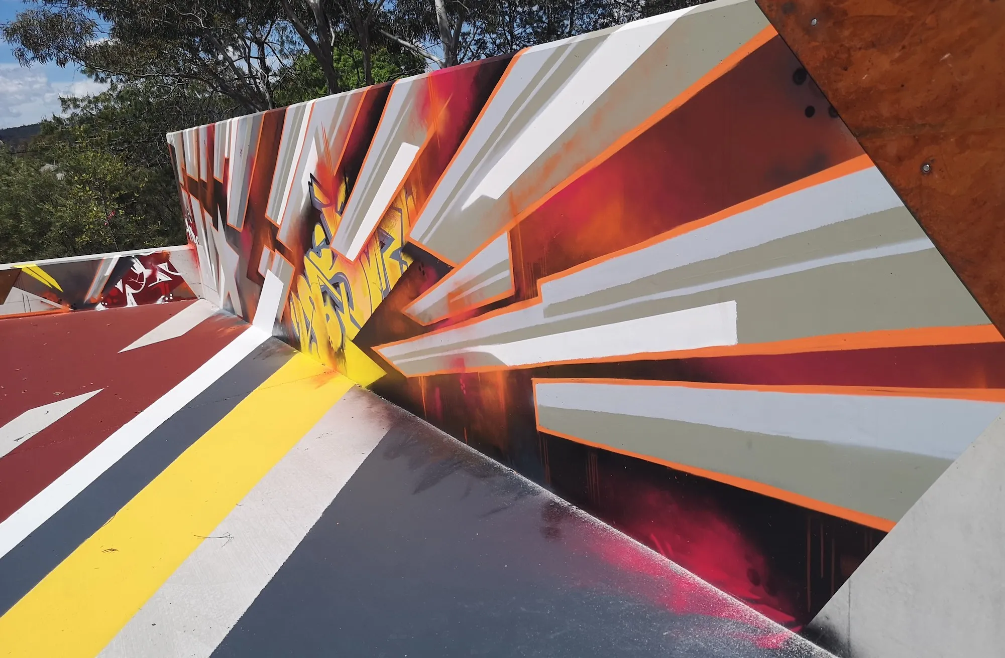 Abstract geometric mural of red, grey and white angled planes across a curved wall